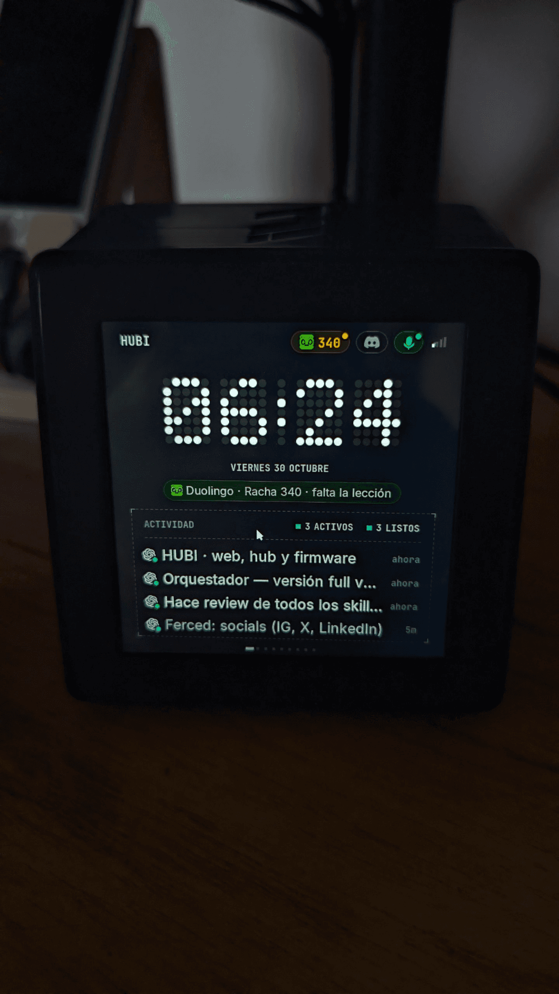 Physical HUBI display showing its clock, Duolingo reminder and coding-agent activity